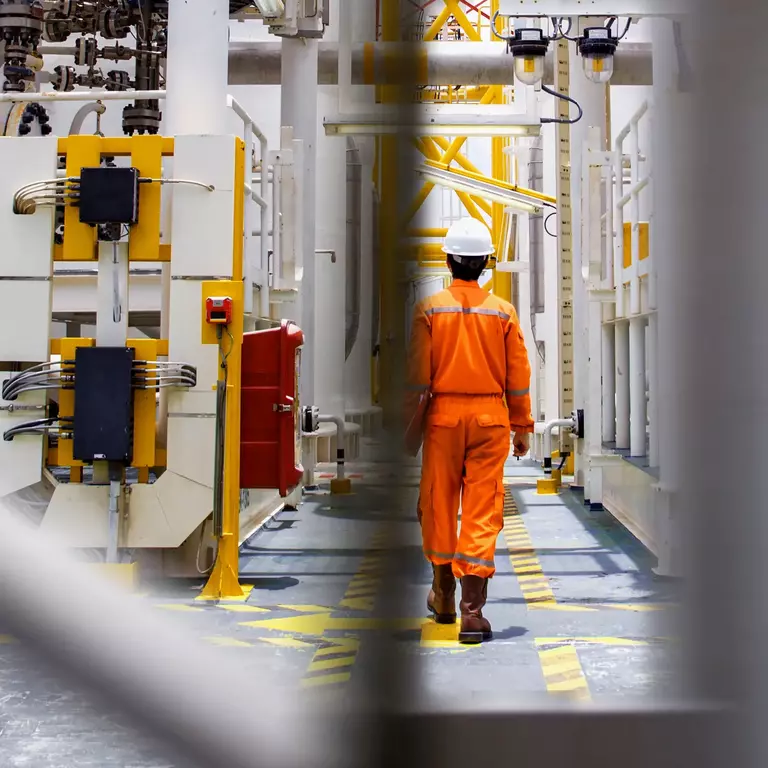 Man with helmet walking throug oil rig
