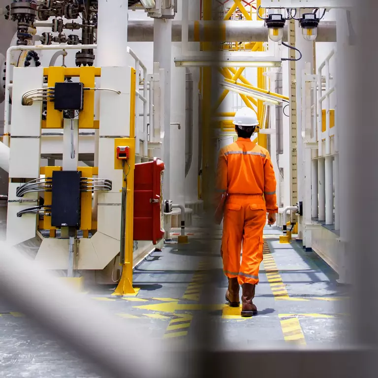 Man with helmet walking throug oil rig