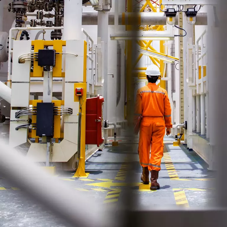 Man with helmet walking throug oil rig
