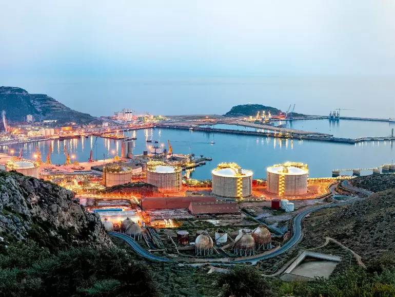 Petrochemical plant and oil refinery industry by the sea at sunset