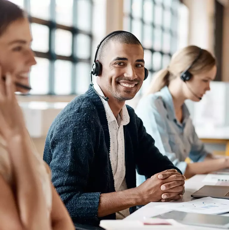 Aufnahme eines jungen Mannes, der ein Headset und einen Computer in einem modernen Büro benutzt