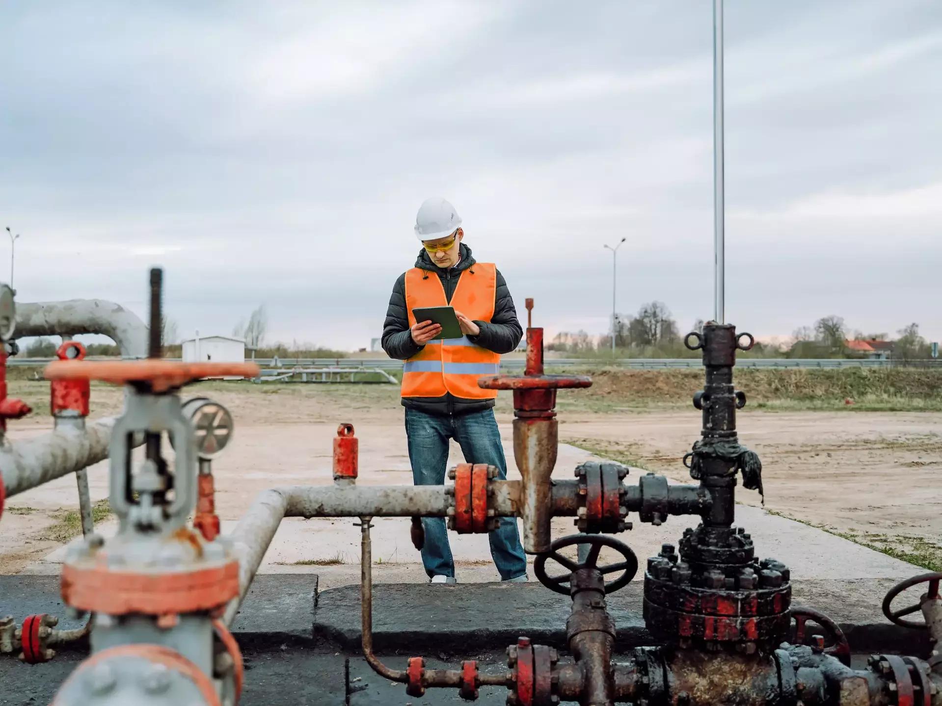 Stationary or technical engineer at work checking valve pipes calculating and analyzing charge of oil and gas in digital tablet Stationary or technical engineer at work checking valve pipes calculating and analyzing charge of oil and gas in digital tablet