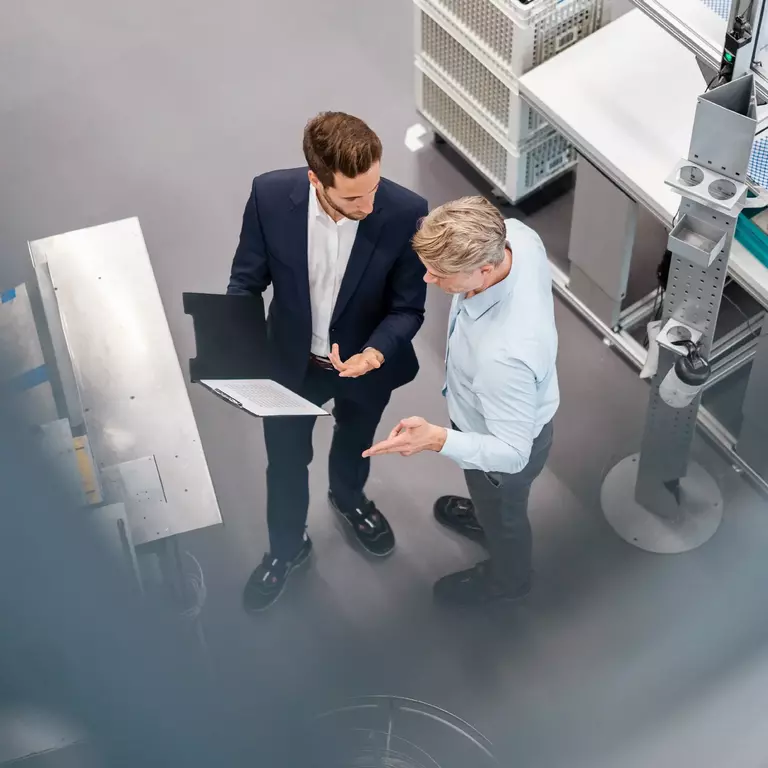 Two businessmen with clipboard talking in a factory