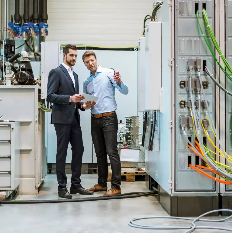 Two businessmen with tablet in factory