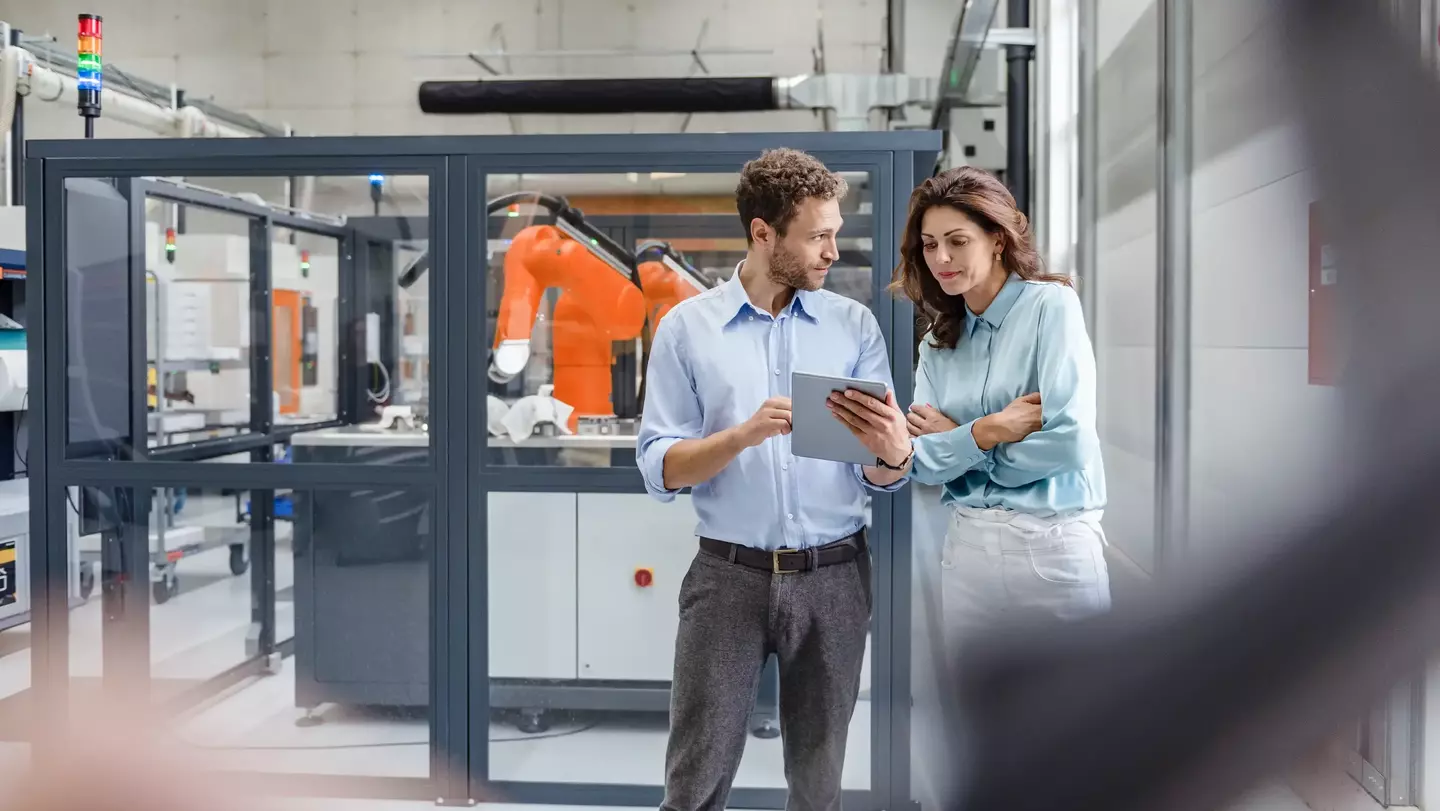 Zwei Kollegen in einem High-Tech-Unternehmen unterhalten sich vor einem industriellen Hintergrund