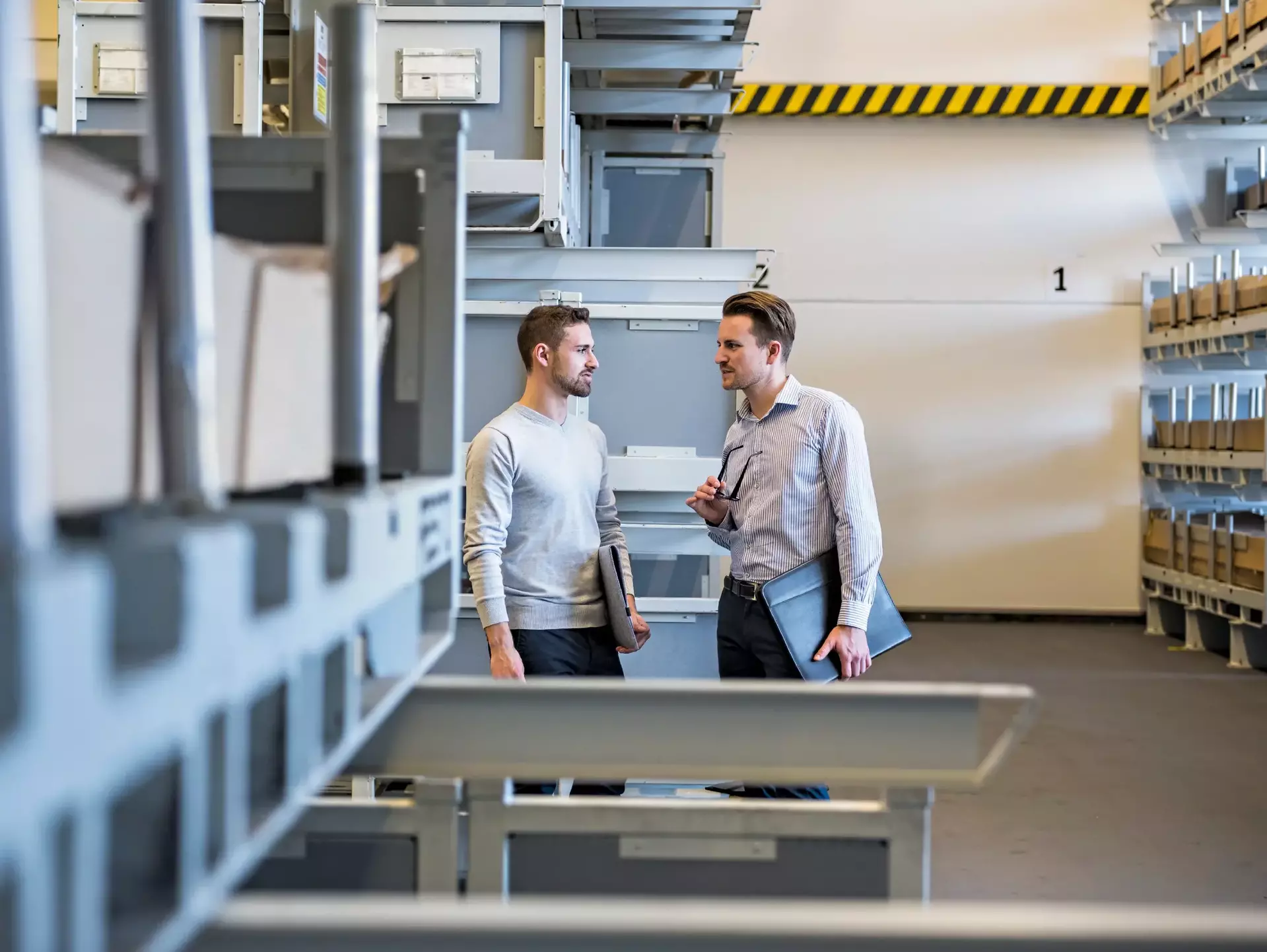 Two men talking in factory warehouse Two men talking in factory warehouse