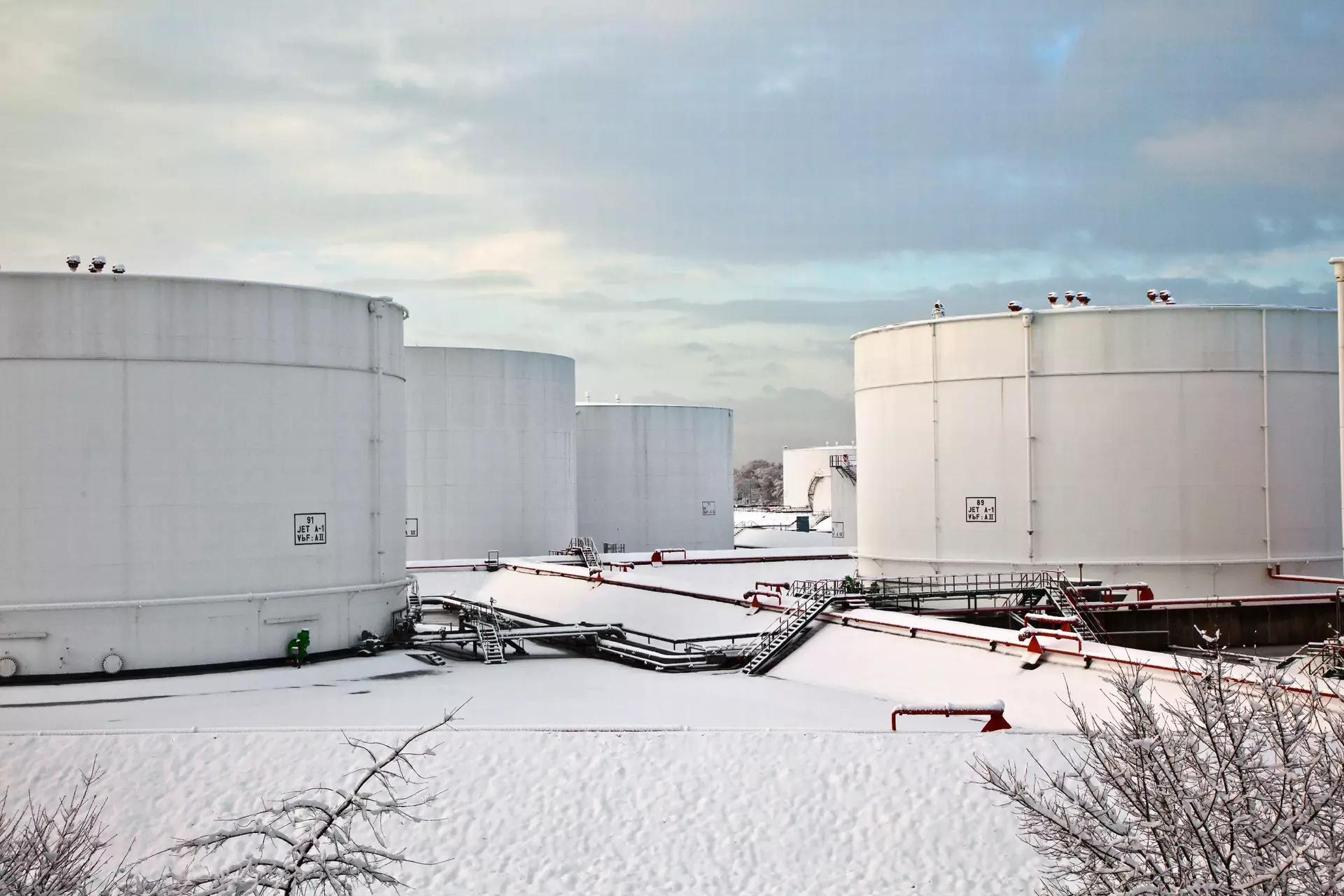 White oil tanks at tank farm with snow in winter White oil tanks at tank farm with snow in winter